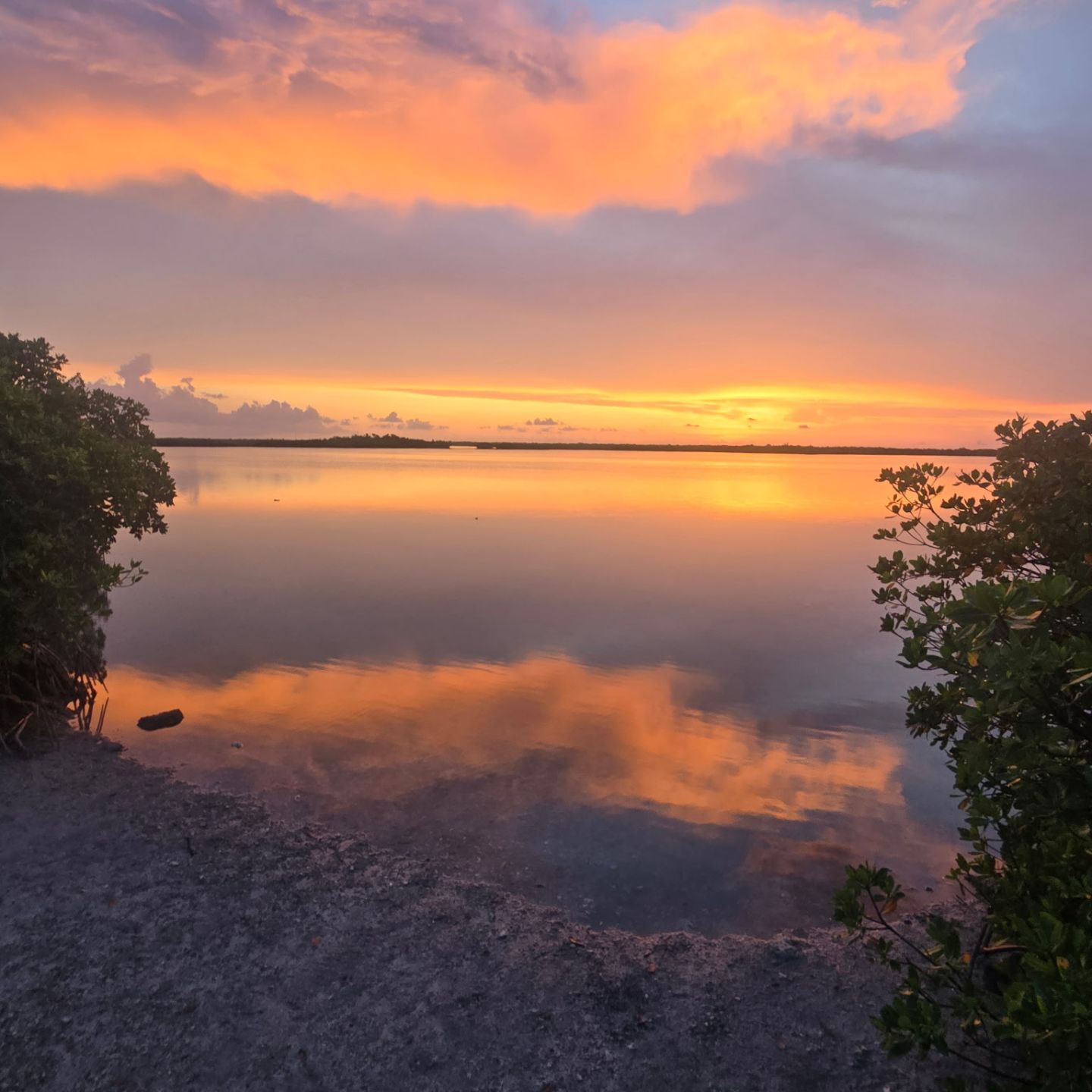 Serene sunset over calm lake with vibrant sky reflections.